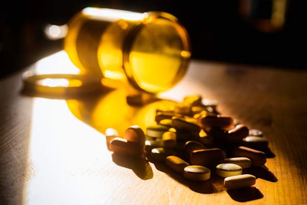 Prescription pills spilled out onto a night stand.