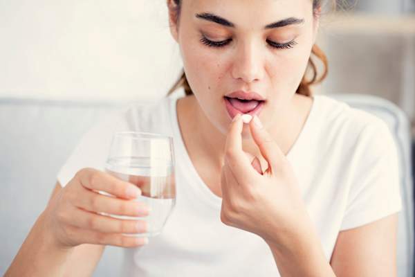 Young woman taking a pill