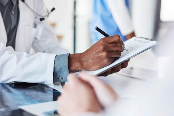 doctor writing out prescription information on chart in hospital
