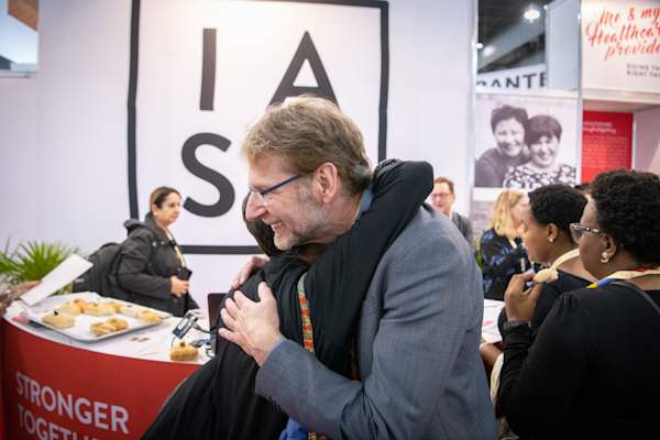 Anton Pozniak, moderator for the IAS 2019 press conference about HIV treatment research, greeting an Educational Fund Scholarship recipient at the IAS Exhibition Booth.