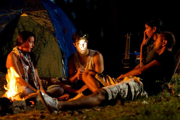 man telling scary story around a campfire