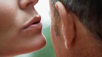Woman whispering into man's ear