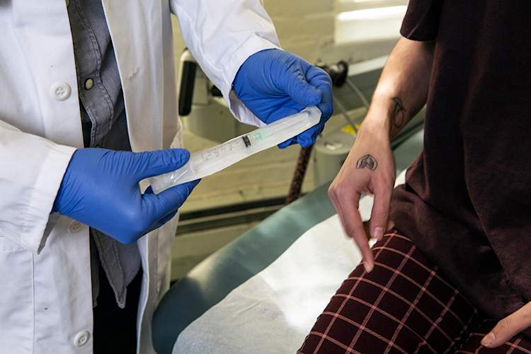 Doctor showing patient syringe for injecting testosterone.