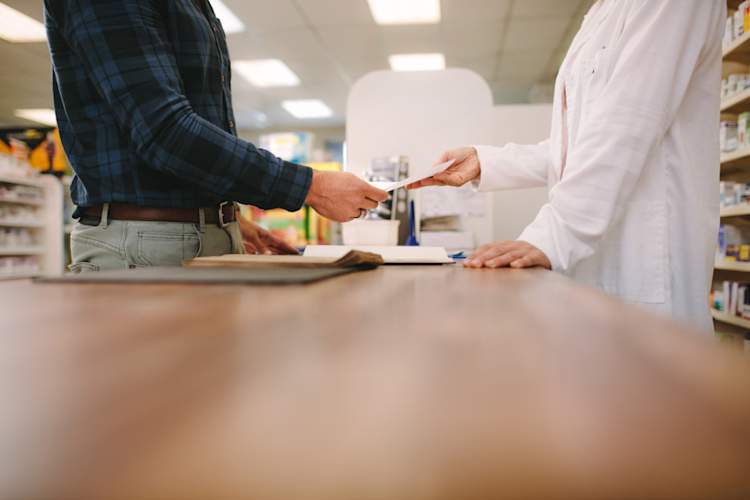 Customer giving medical prescription to pharmacist