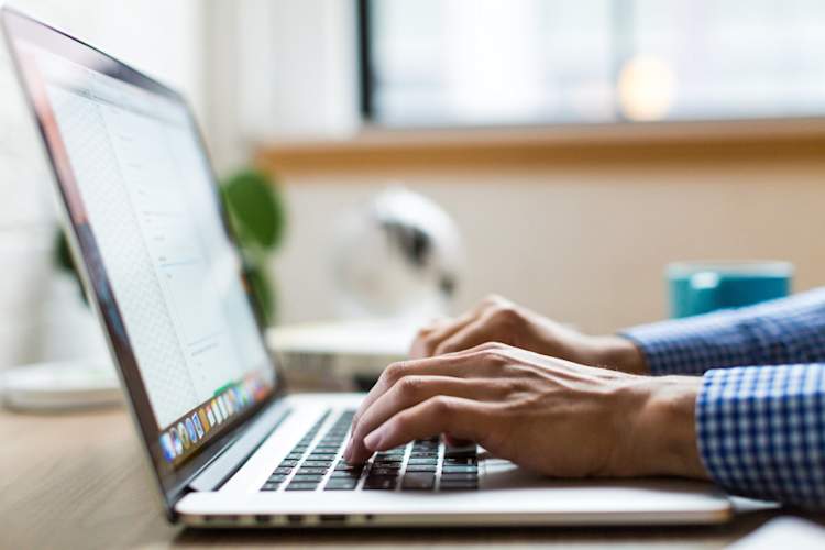 man's hands typing on laptop