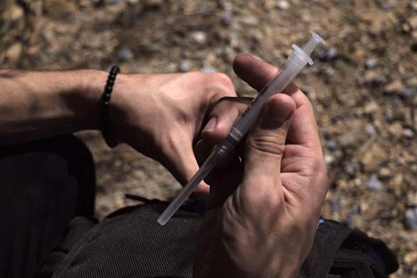 Close up of man's hands holding syringe