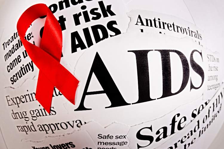 red ribbon on top of newspaper clippings about HIV/AIDS