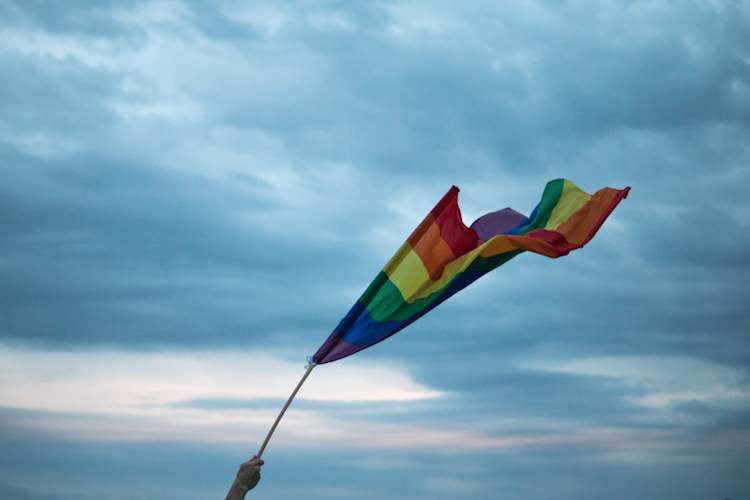 Gay pride flag waving against sky