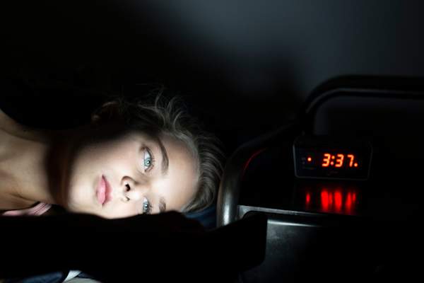 Girl with insomnia, light shining on her face, clock says 3:37AM