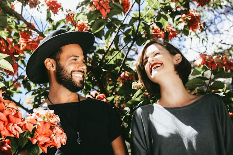 heterosexual couple smiling under flowering trees