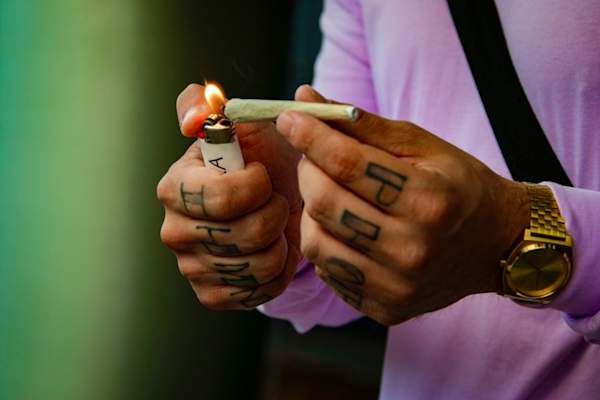 Man with knuckle tattoos lighting a joint