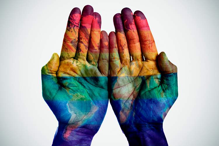 World map and rainbow flag on hands