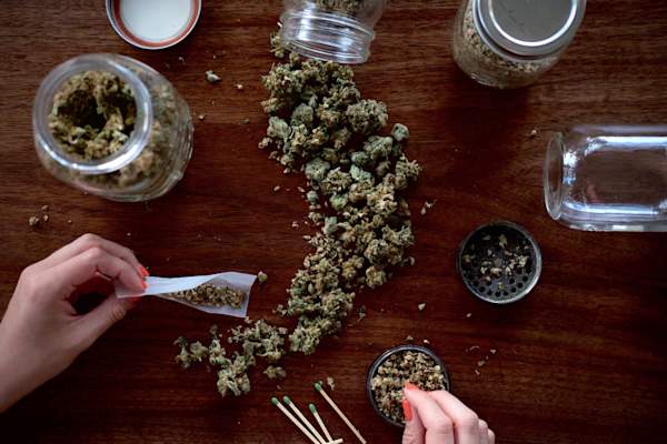 person rolling joint, focus on hands, cannabis on table