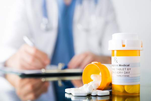 doctor with two prescription bottles, one with white pills spilling out