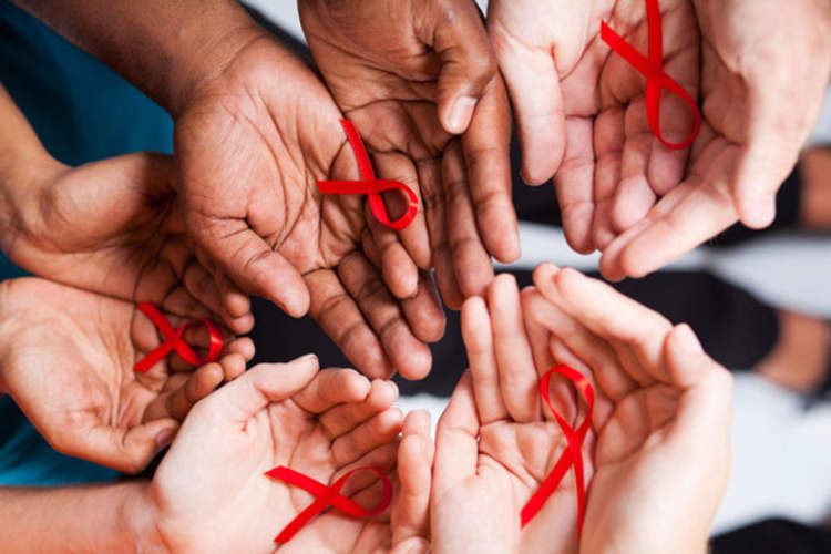 Multiracial people holding red ribbons