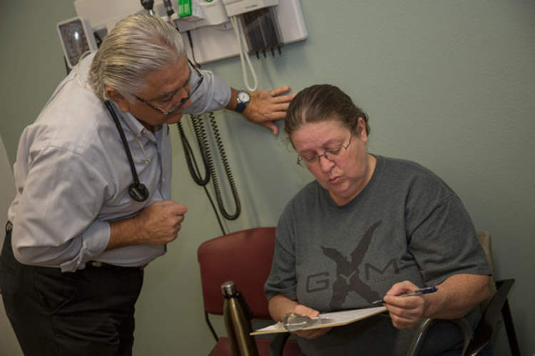 Dr. Ronald Cirillo helps Deborah Hatfield fill out paperwork at a Florida clinic before running a test to see whether she has hepatitis C