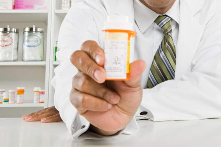 A pharmacist's hand holding a pill bottle