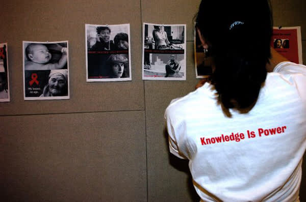 A student pins an HIV flyer to the wall