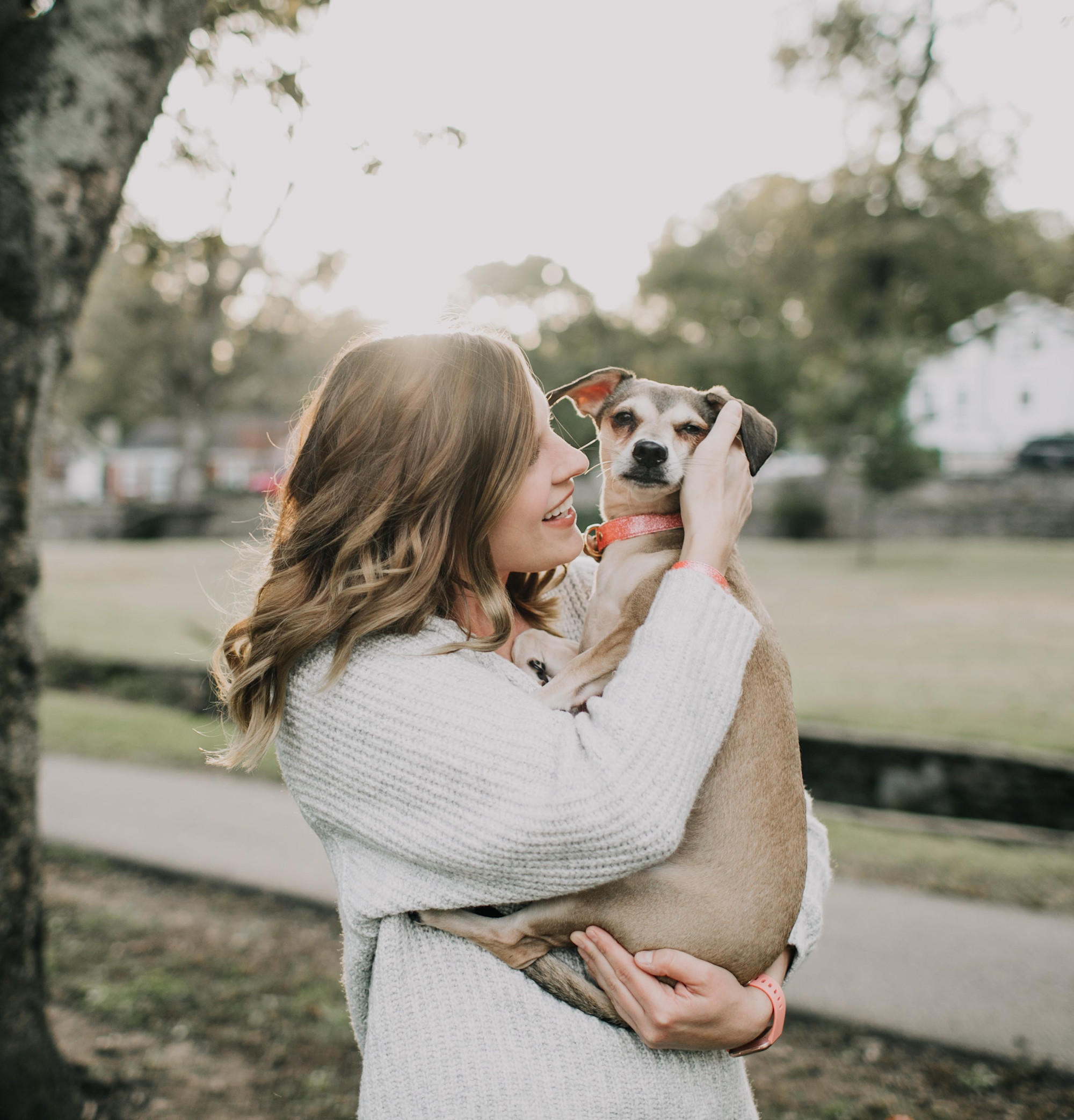 A woman holding a dog outside.