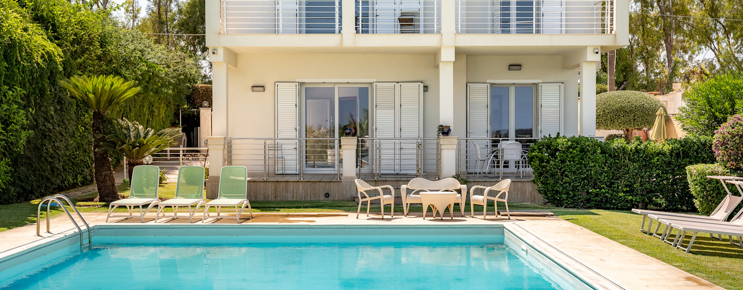 The pooled exterior of a villa in Syracuse managed by Wonderful Italy, surrounded by a large private garden