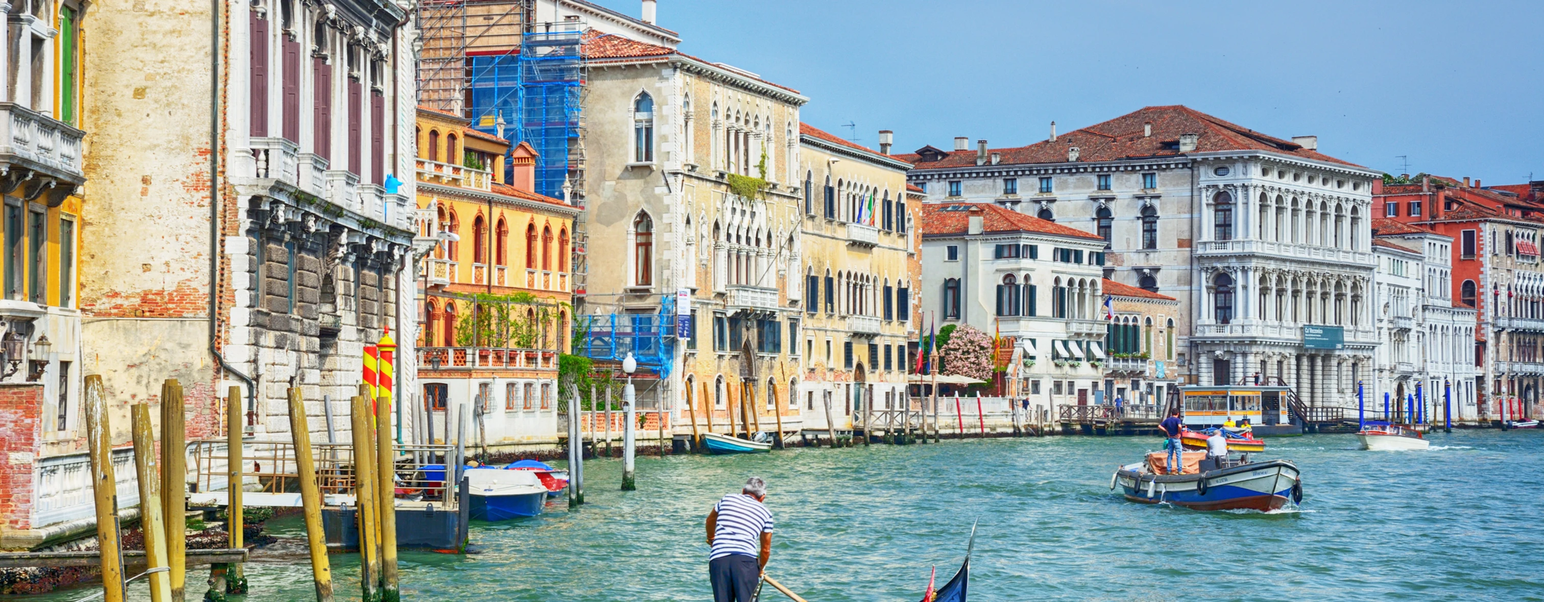 A gondolier guides a gondola through the calle of Venice