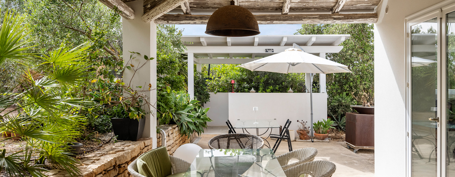 Patio esterno con tavolo, sedie e ombrellone di una villa in Sicilia