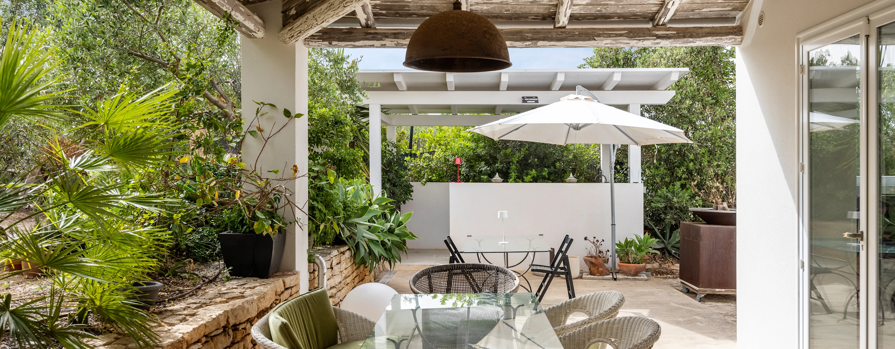Outdoor patio with table, chairs and umbrella of a villa in Sicily