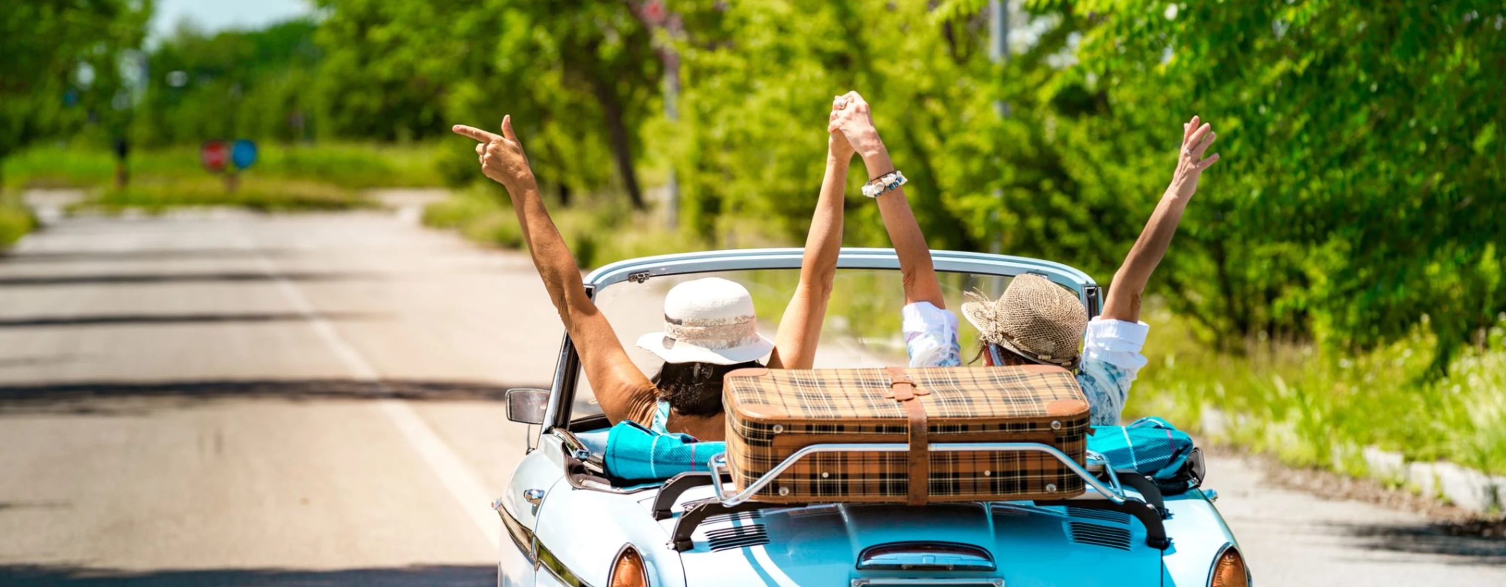 Due amiche gioiscono guidando un'auto vintage durante un viaggio in Italia