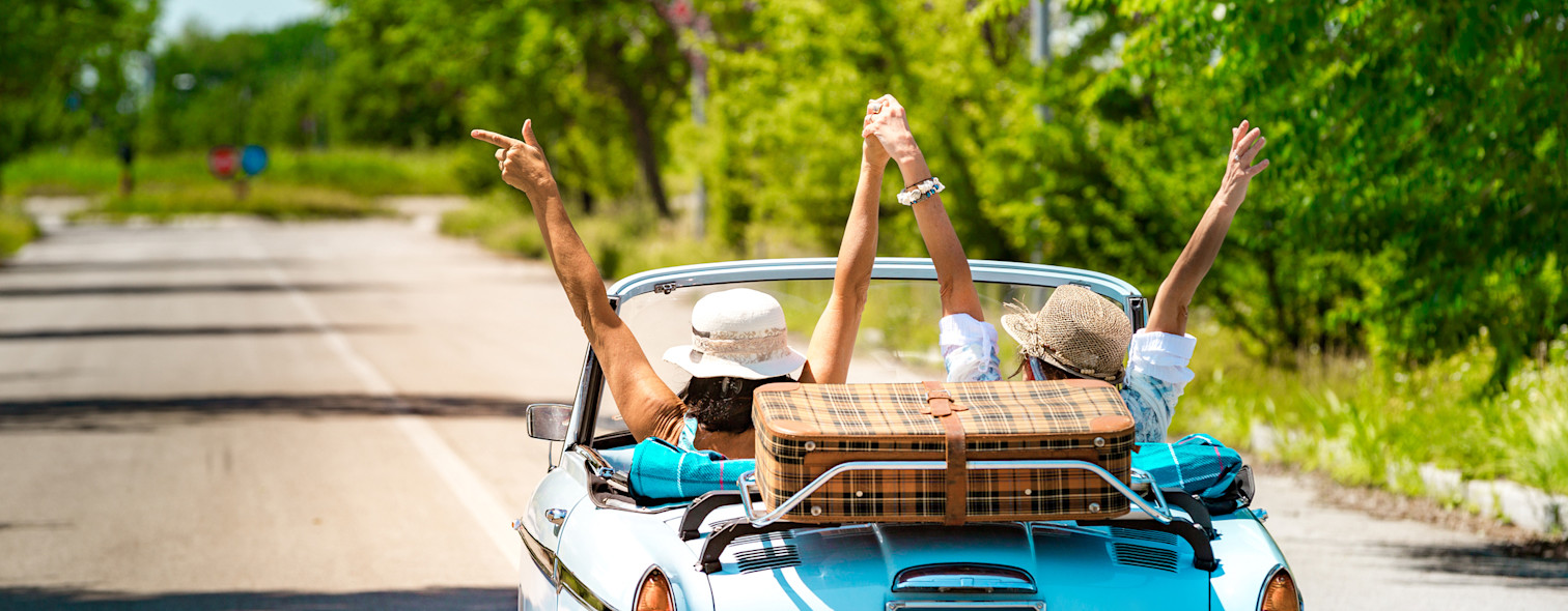 Two friends rejoice driving a vintage car during a trip to Italy