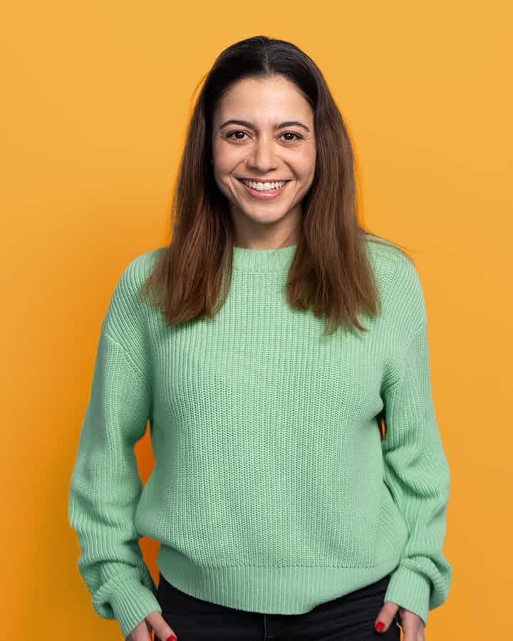 Woman smiling at camera on yellow background (large card - 3col)