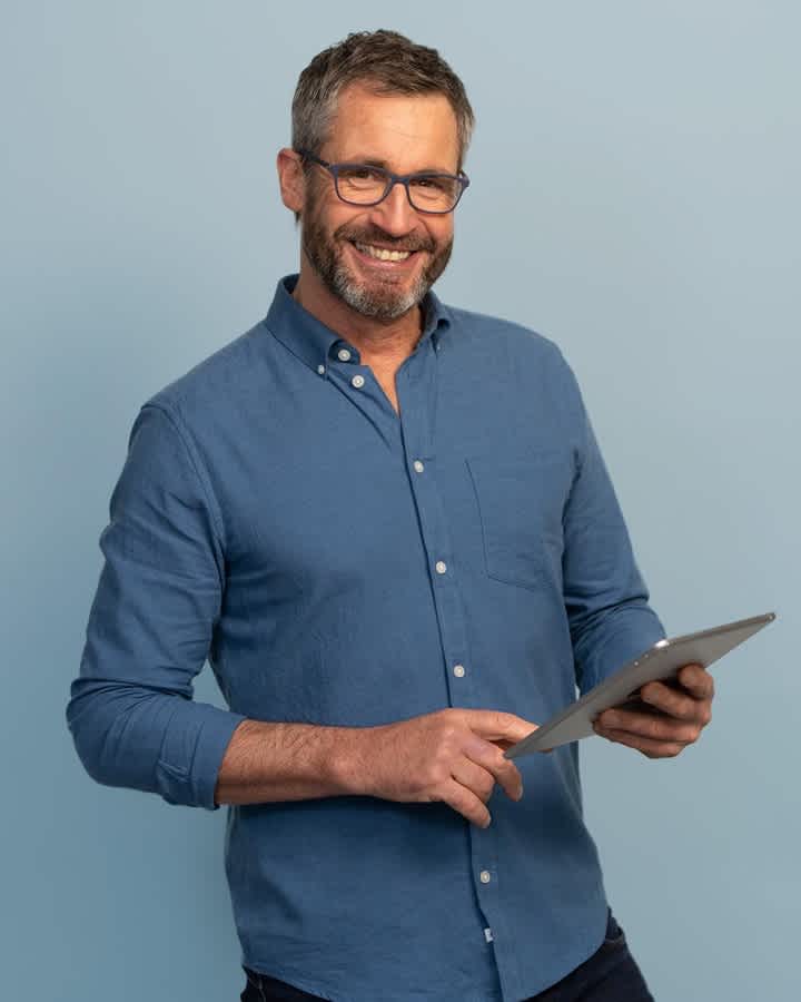 Man holding tablet and smiling at camera (large card)
