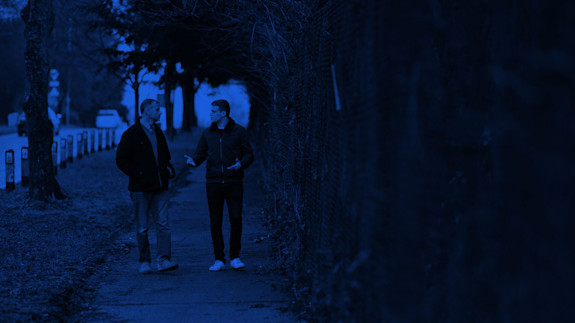 Hero image | FAQ page Two people deep in conversation, walking down a path
