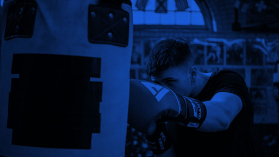 Hero image | Stories page Man wearing boxing gloves punching a punching bag