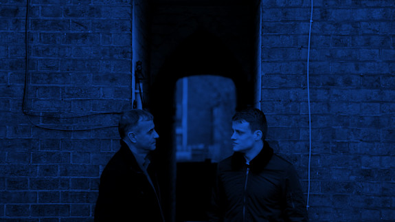Hero image | About us Two people deep in conversation leaning against a wall