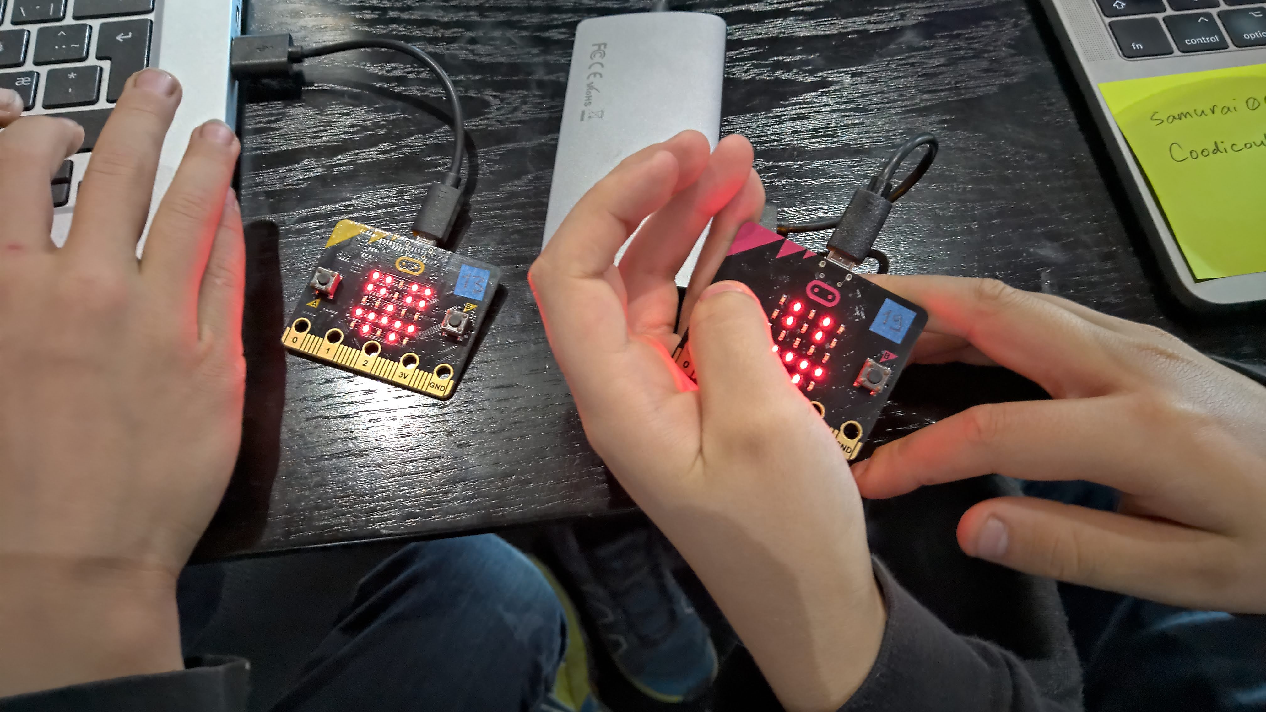 Two kids holding micro:bit computers with red illuminated led lights