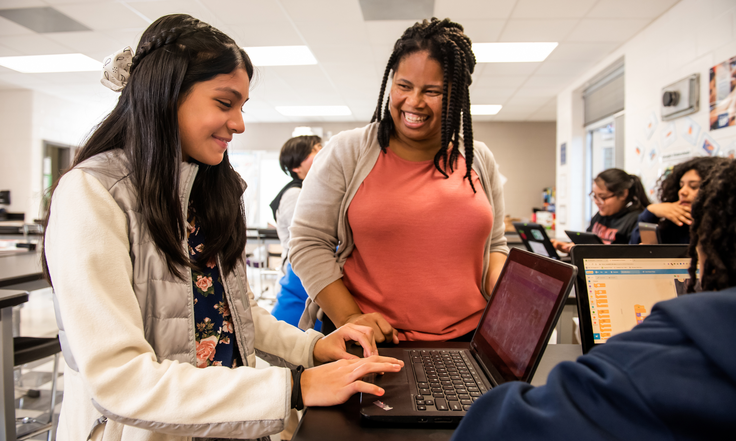 A girl codes beside her Code Club leader at a Code Club in the USA