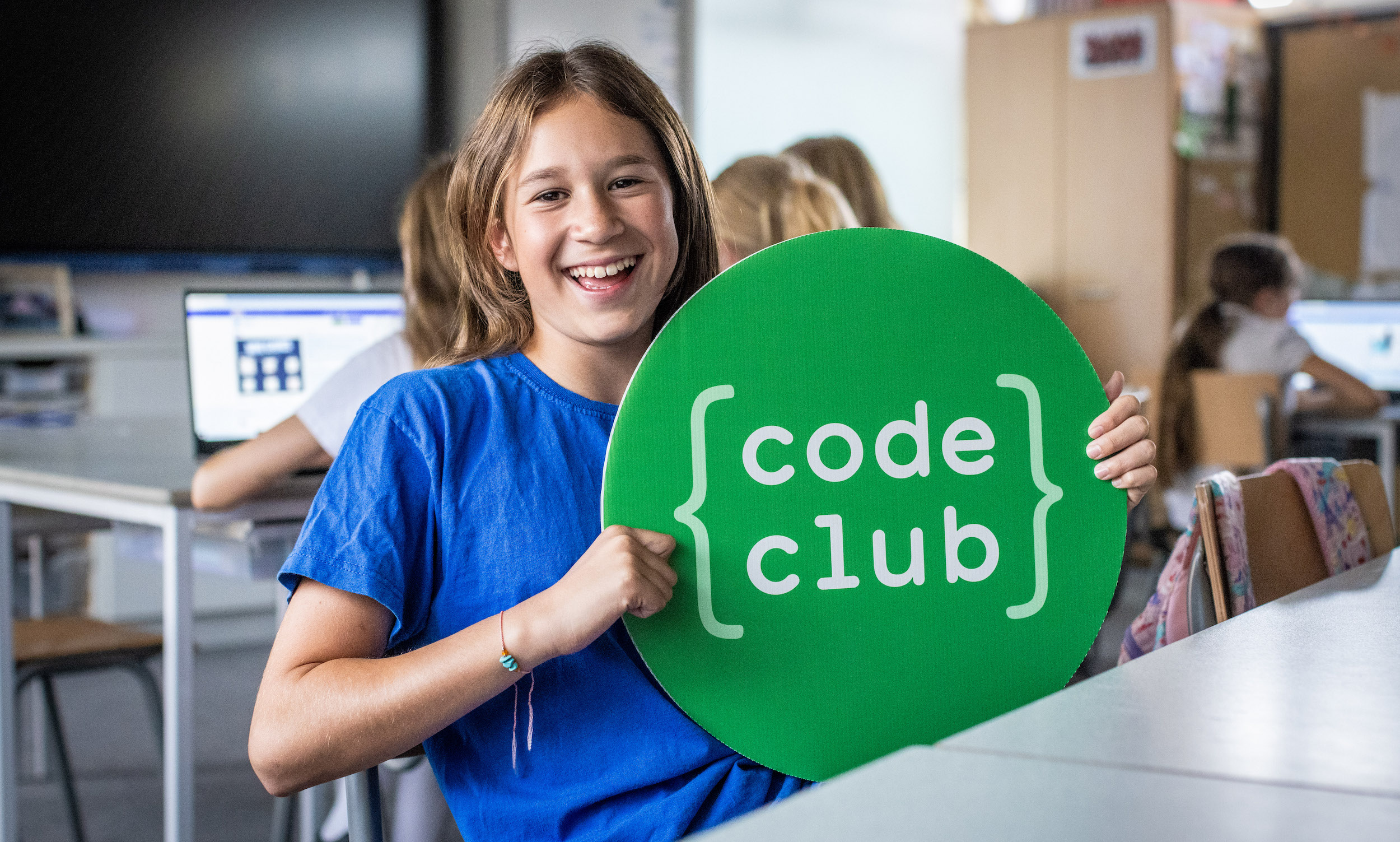 Girl attending a Code Club and holding a Code Club sign