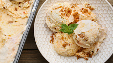 Peach ice cream scoops in patterned bowl, sprinkled with cookie crumbs and a mint sprig