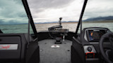 Boat bow with trolling motor and fishfinder on lake, mountains and cloudy sky