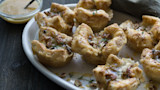Wild-game puff pastry cups on white plate drizzled with honey and sprinkled with pecans
