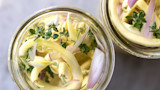 Two jars of quick pickles: yellow wax beans, sliced shallot and thyme in clear brine