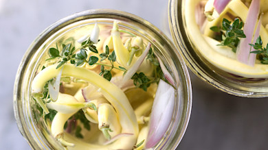 Two jars of quick pickles: yellow wax beans, sliced shallot and thyme in clear brine