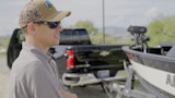 Man in camo cap and sunglasses by pickup truck and boat trailer