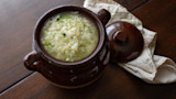 Sauerkraut in a brown ceramic pot with lid and a folded cloth napkin