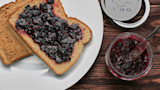 Two slices of toast, one topped with dark berry jam; jar with spoon and lid marked "1/30/22"
