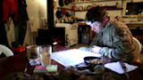 Man with headlamp studying illuminated map on a table in a hunting cabin