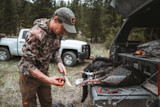 Hunter cleaning turkeys and a bear on pickup tailgate, bloody hands holding a knife