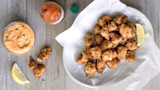 Fried alligator bites with remoulade, lemon wedges, and hot sauce