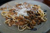 Spaghetti with ground meat sauce and grated Parmesan on a gray plate