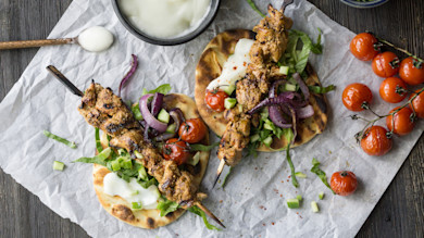 Grilled pheasant skewers on charred flatbread with yogurt, roasted cherry tomatoes, red onion and diced cucumber